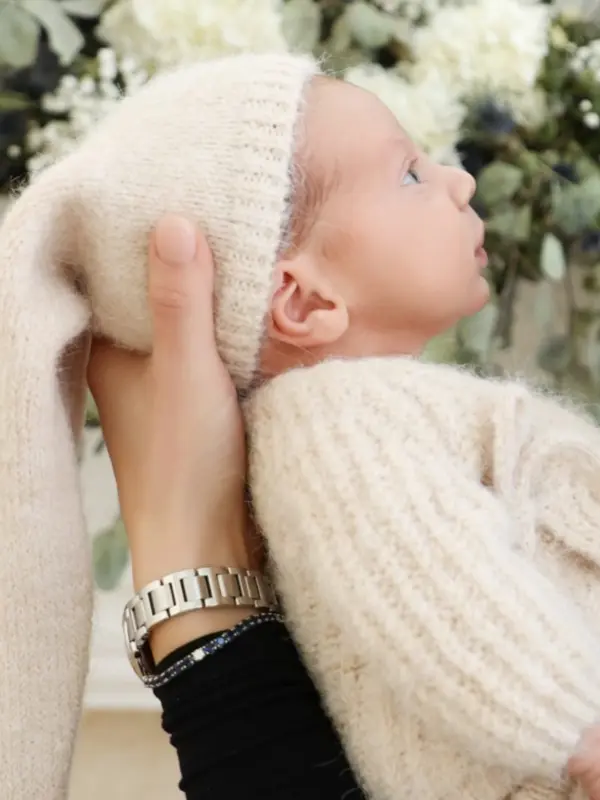 Newborn photography Monsey NY – Newborn in a cream knit hat held in a parent's hands