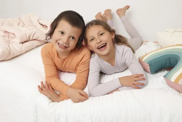 Brother and sister lying on a bed, smiling, studio photography by Photoholic, Monsey NY